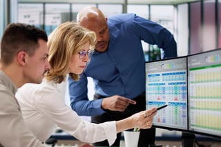 Supervisor checking data quality dashboard on monitor